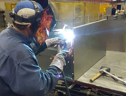 Image of a Dana Precision employee welding a piece of metal.